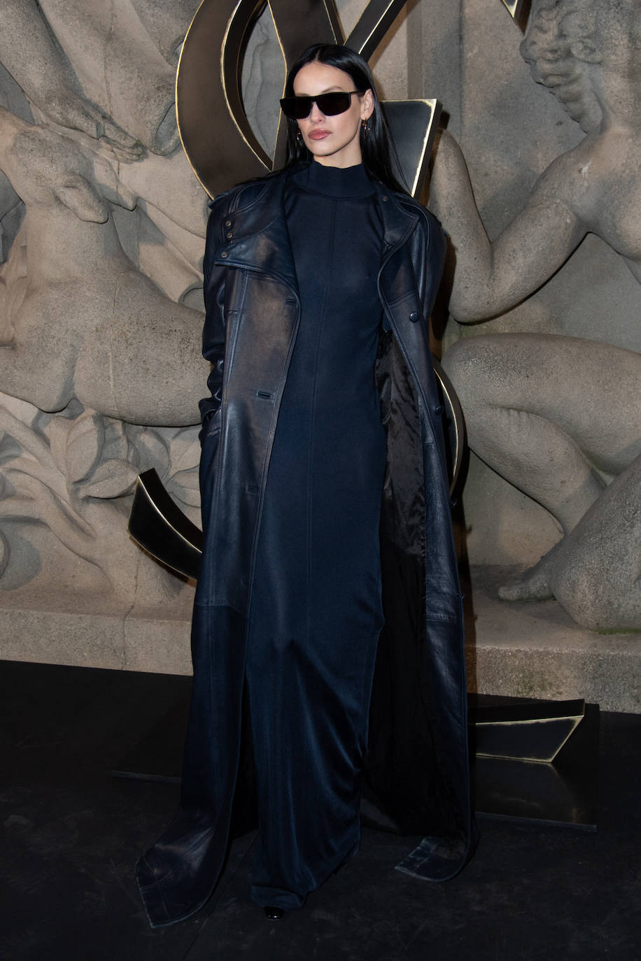 Milena Smit de Saint Laurent con vestido negro transparente y gabardina de piel. 