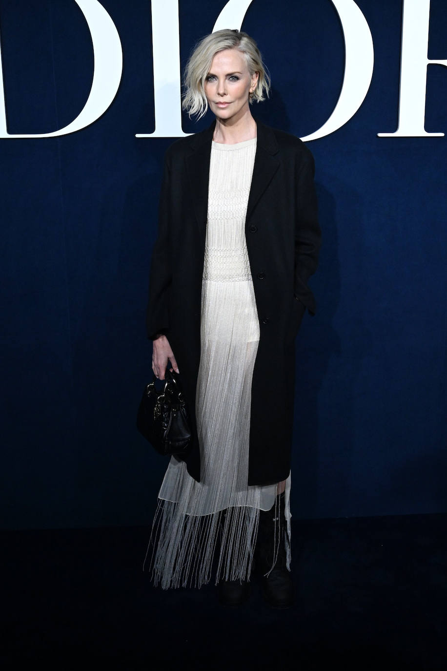 Charlize Theron acudió al desfile de Dior con vestido blanco de flecos. 