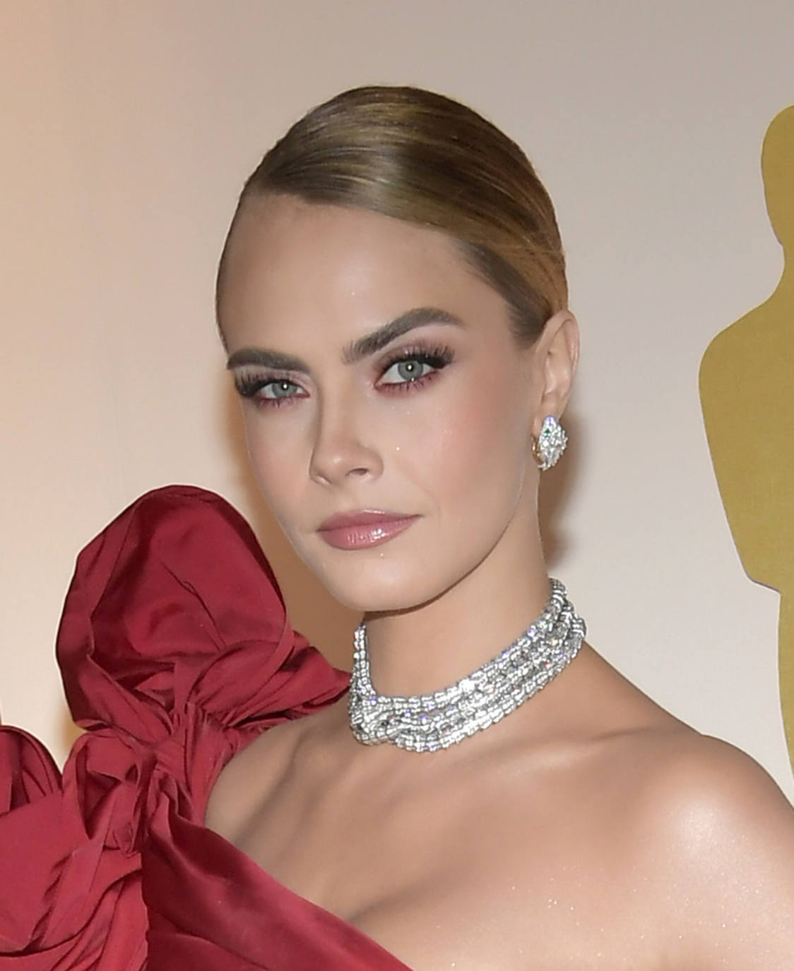 Cara Delevingne llevó un moño bajo muy pulido y con raya lateral, y un bonito maquillaje en tonos rosas. 