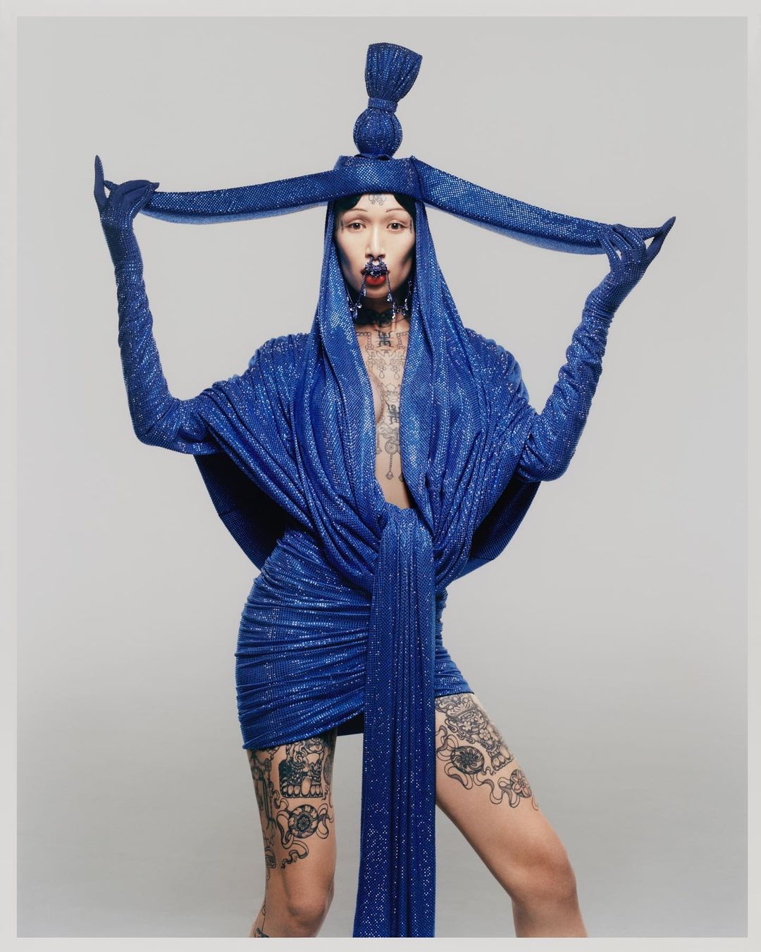 Vestido drapeado en punto termo-strass azul. Gorro de termostrass a juego y tocado. 