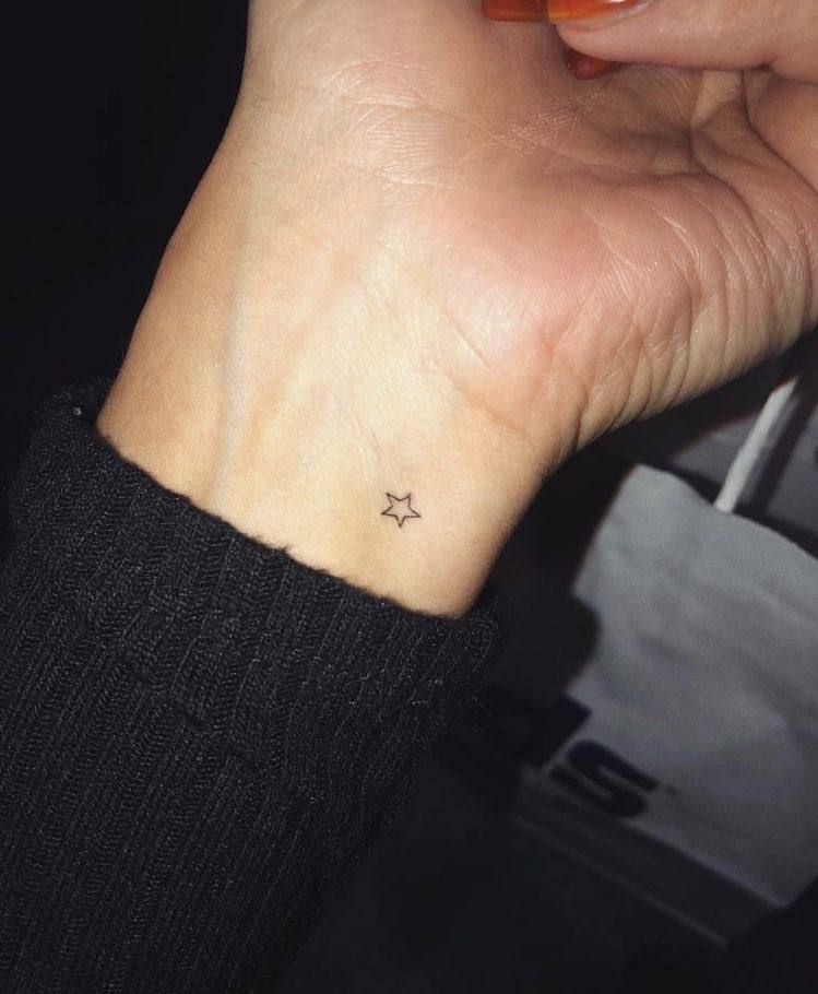 Tatuaje pequeño con línea fina de una estrella en la zona interior de la muñeca.