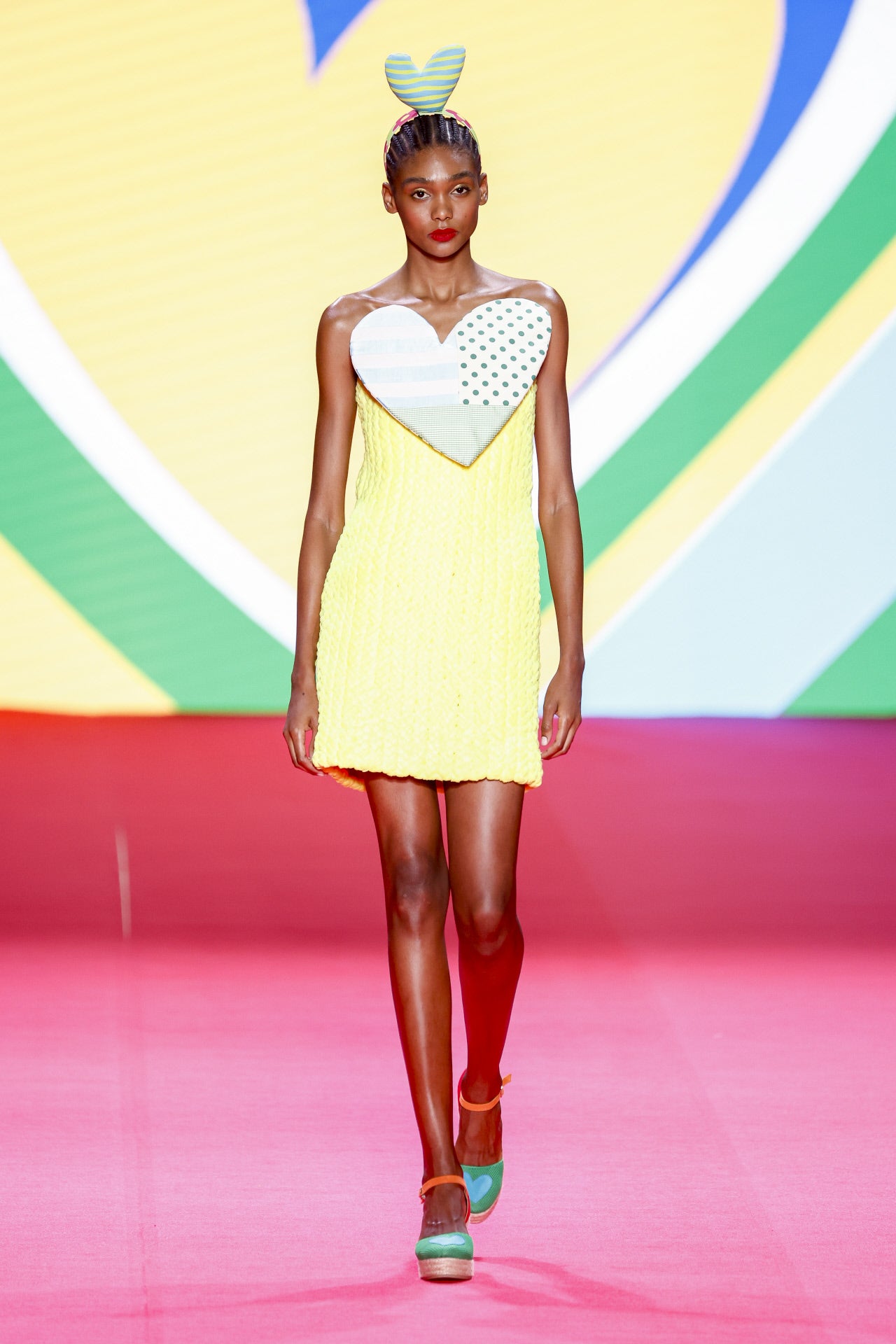 Desfile de Ágatha Ruiz de la Prada en la MBFWMadrid primavera-verano 2024. No podían faltar tampoco el año que viene sus conocidos corazones en tamaño XL sobre cualquiera de sus piezas. En esta ocasión vemos un vestido mini en amarillo, uno de los colores más vistos en su próxima colección, y lleva esta forma en la parte del pecho.