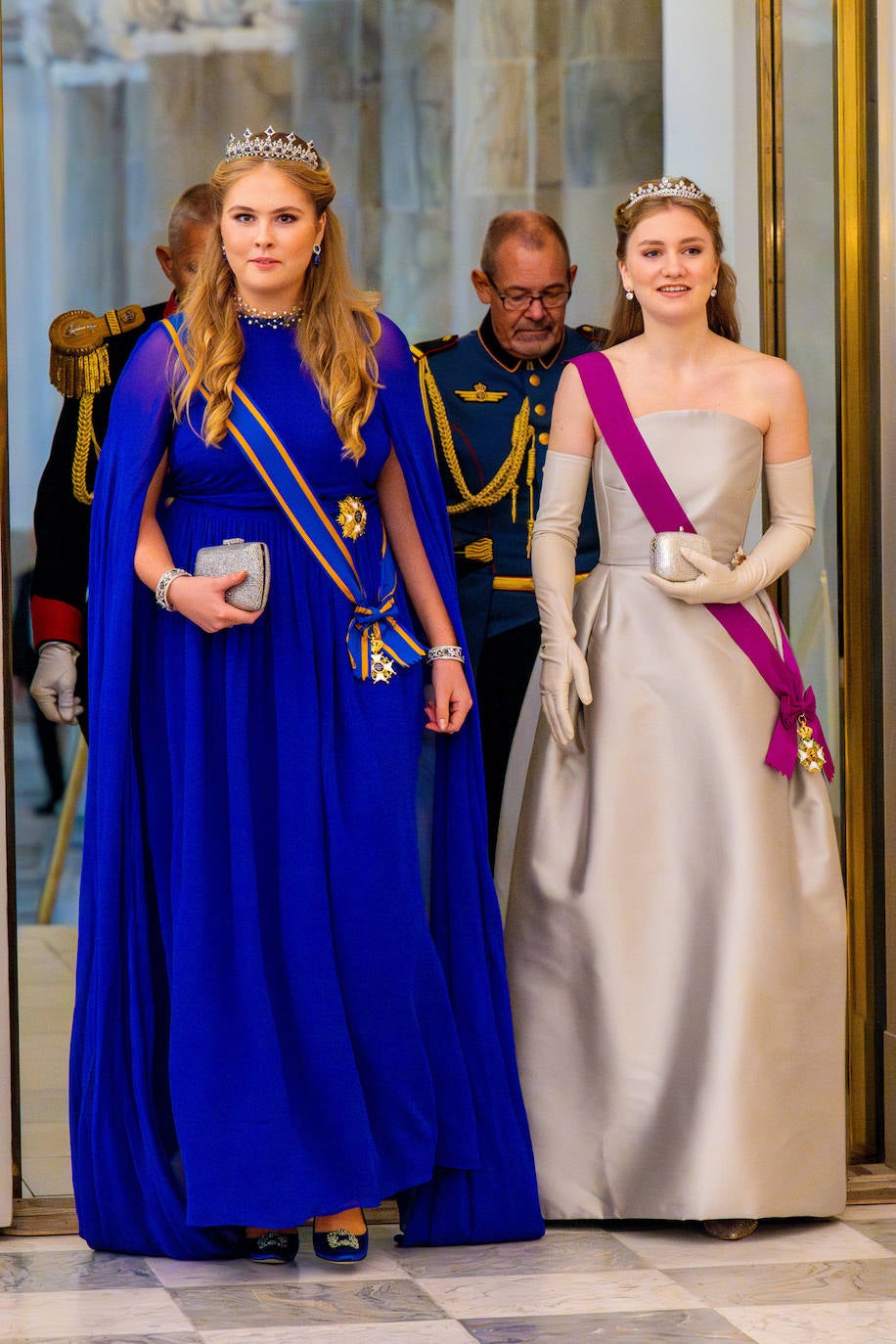 Amalia de Holanda llevó un vestido capa en color azul de Essential Antwerp y zapatos de Manolo Blahnik. En cuanto a las joyas, la heredera de los Países Bajos, se decantó por una bonita tiara a juego con los pendientes, ambos con piedras azules. Por su parte, Elizabeth de Bélgica eligió un vestido con escote palabra de honor de Natan Couture, a juego con los guantes, zapatos de tacón de Georgio Armani y la tiara Wolfer. 