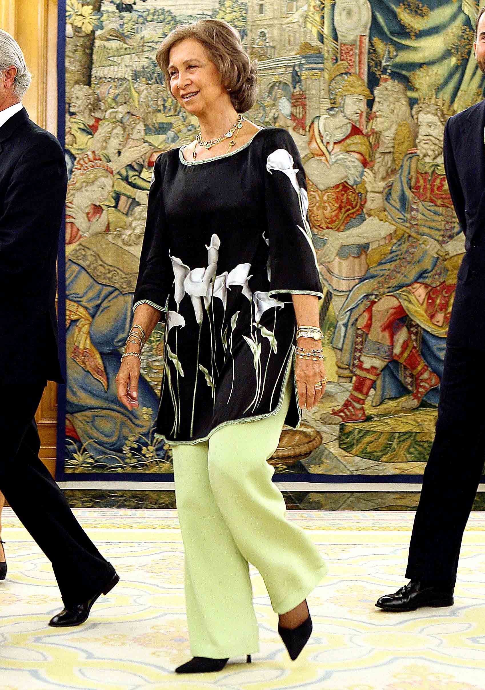 Doña Sofía, con un atuendo formado por una túnica con flores y un pantalón campana verde. 