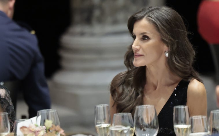 Imagen principal - La Reina Letizia con vestido negro de lentejuelas de Rotate, una firma danesa; y pendientes chatones, una de las «joyas de pasar» de la Casa Real