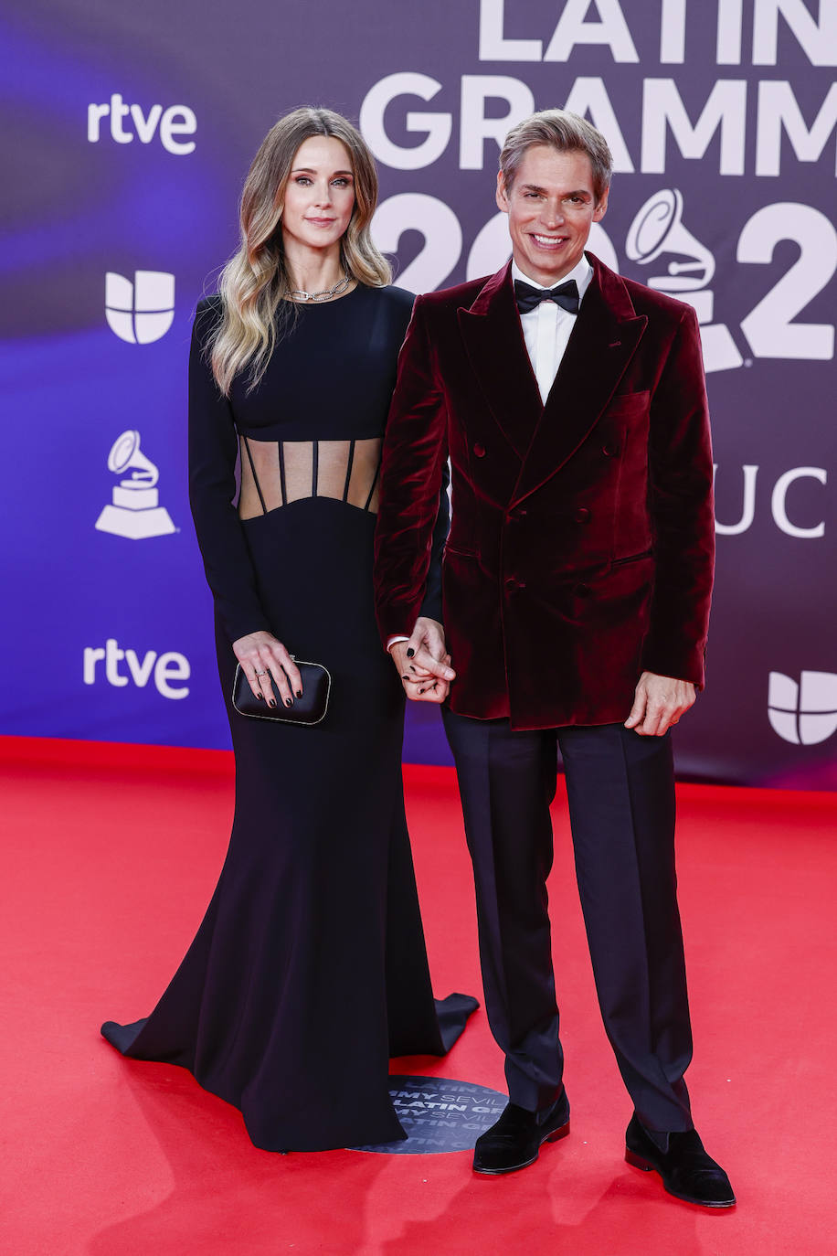 Carlos Baute, con chaqueta de terciopelo en color burdeos, y Astrid Klisans con vestido negro con transparencias en la parte del abdomen de Yolancris.