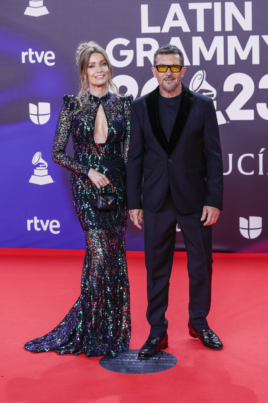 Antonio Banderas ha combinado su traje con camiseta, todo en negro. Su pareja, Nicole Kimpel, ha lucido un vestido de lentejuelas con escote lágrima. 