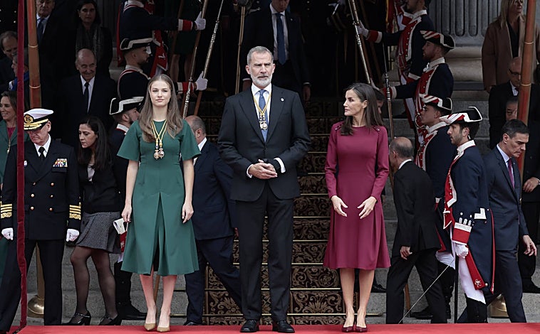 Imagen principal - La Reina ha derrochado elegancia con un vestido burdeos y complementos del mismo tono. 