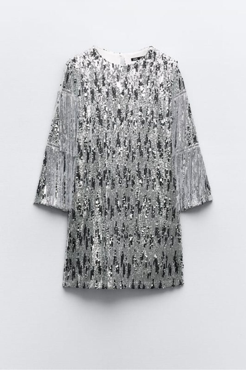 Zara. Minivestido de estilo setentero con el cuello redondo y manga larga con aplicación de flecos en toda la pieza. Precio: 39,95€.