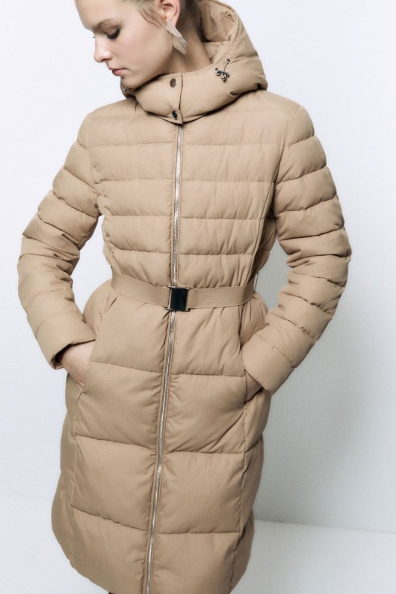 Sfera. Abrigo acolchado con capucha y cinturón en tonos beige de tipo plumífero. Precio: 79,99€.