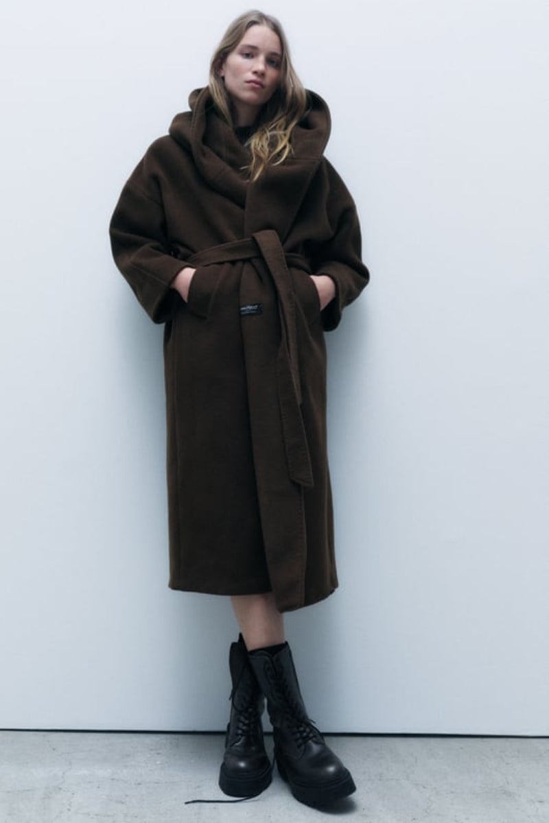 Zara. Abrigo marrón chocolate con capucha confeccionado en hilatura con mezcla de lana, manga larga y bolsillos delanteros. Precio: 169€.