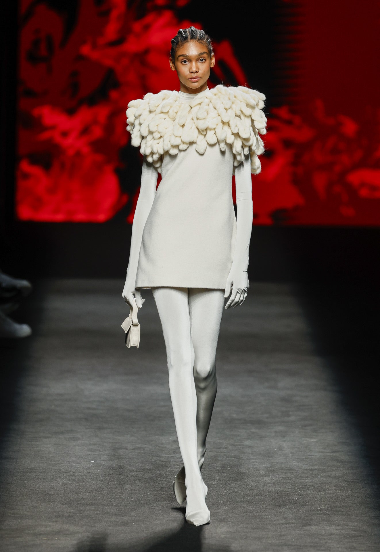 MBFWMadrid: Claro Couture (Otoño/Invierno 2024-2025). Los ejidos lujosos y suaves (como el satén, la seda y el terciopelo) se han dejado ver en todo tipo de tonalidades, como este vestido corto voluminoso. El bolso es de la firma The Lunch bag.