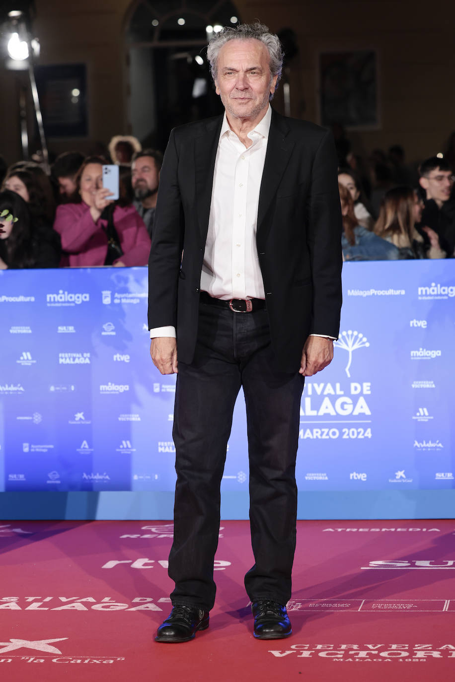 José Coronado con traje de chaqueta negro, camisa blanca y sin corbata. 