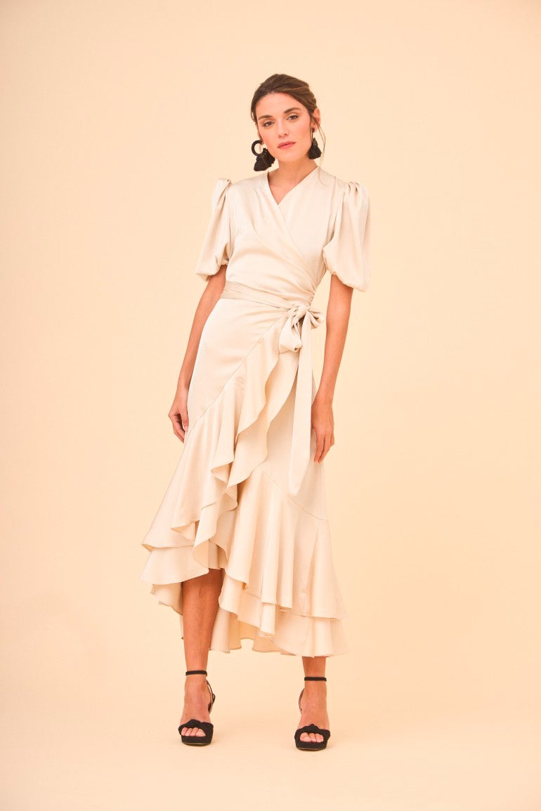 Vestido asimétrico de manga corta y falda estilo pareo confeccionado en tela satinada de color crudo. 170 euros en Coosy.