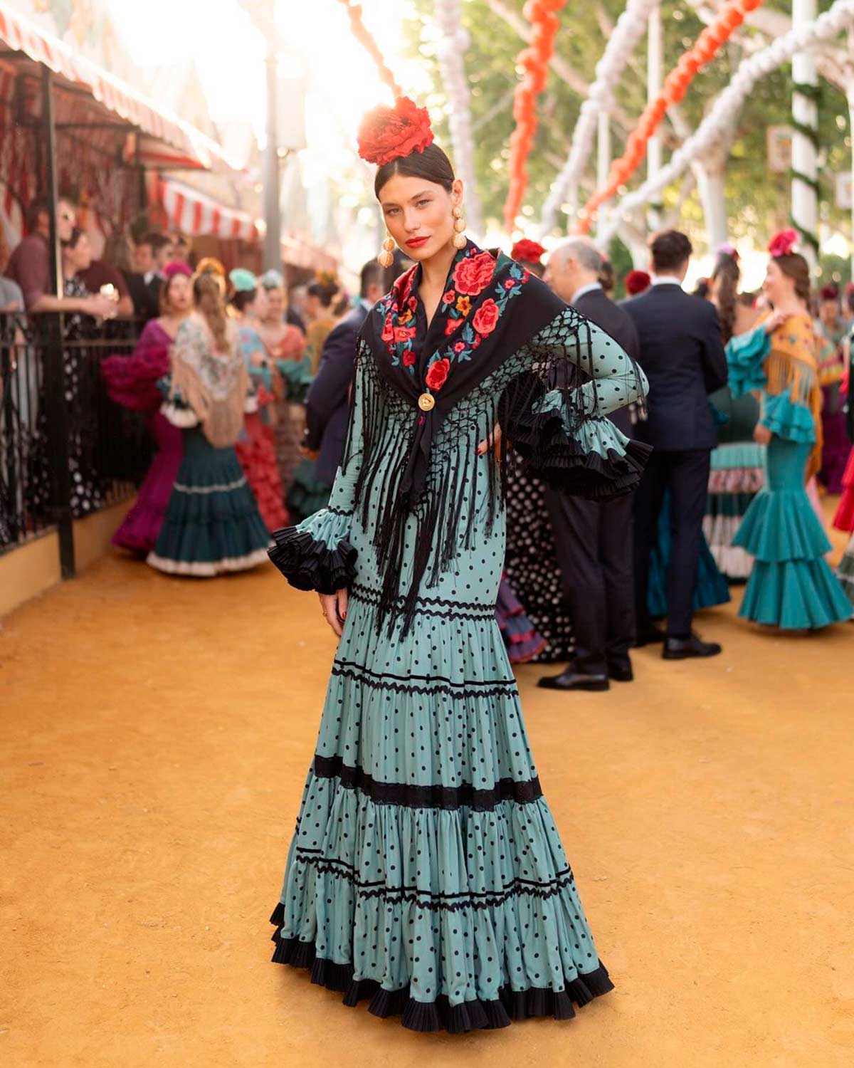 Carmen Santa Cruz apostó por un vestido canastero de Rocío Peralta en color azul verdoso y con pequeños lunares en negro. El mantón, con flores rojas al igual que la flor de la cabeza. 