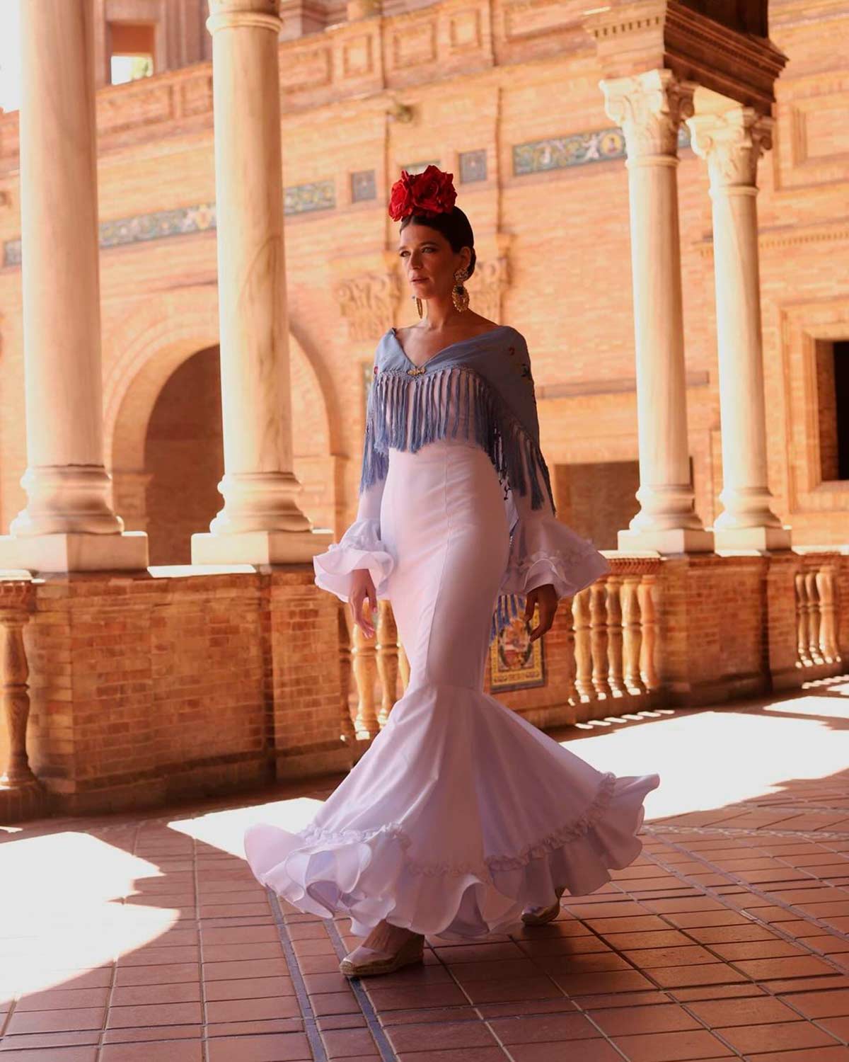 Raquel Martínez combinó un vestido blanco con un mantón azul y flores rojas en el pelo. El traje, firmado por Sibilina Flamenca. 
