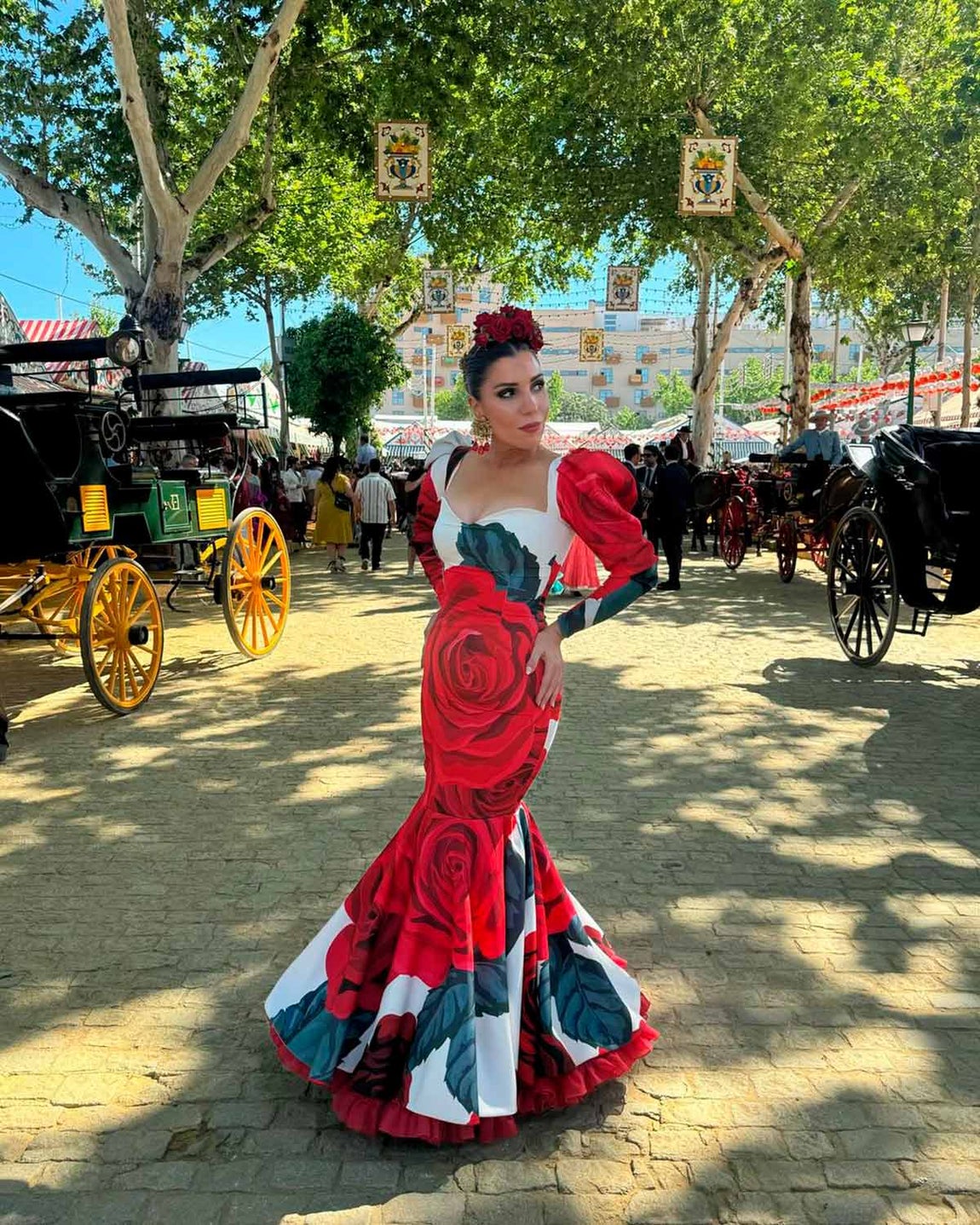 La 'influencer' Margarita de Guzmán apostó por un espectacular traje con estampado floral firmado por Rosa Pedroche. El diseño, entallado, presenta mangas abullonadas en la zona de los hombros y un escote de lo más favorecedor. Lo combinó con joyas en el pelo y flores rojas. 