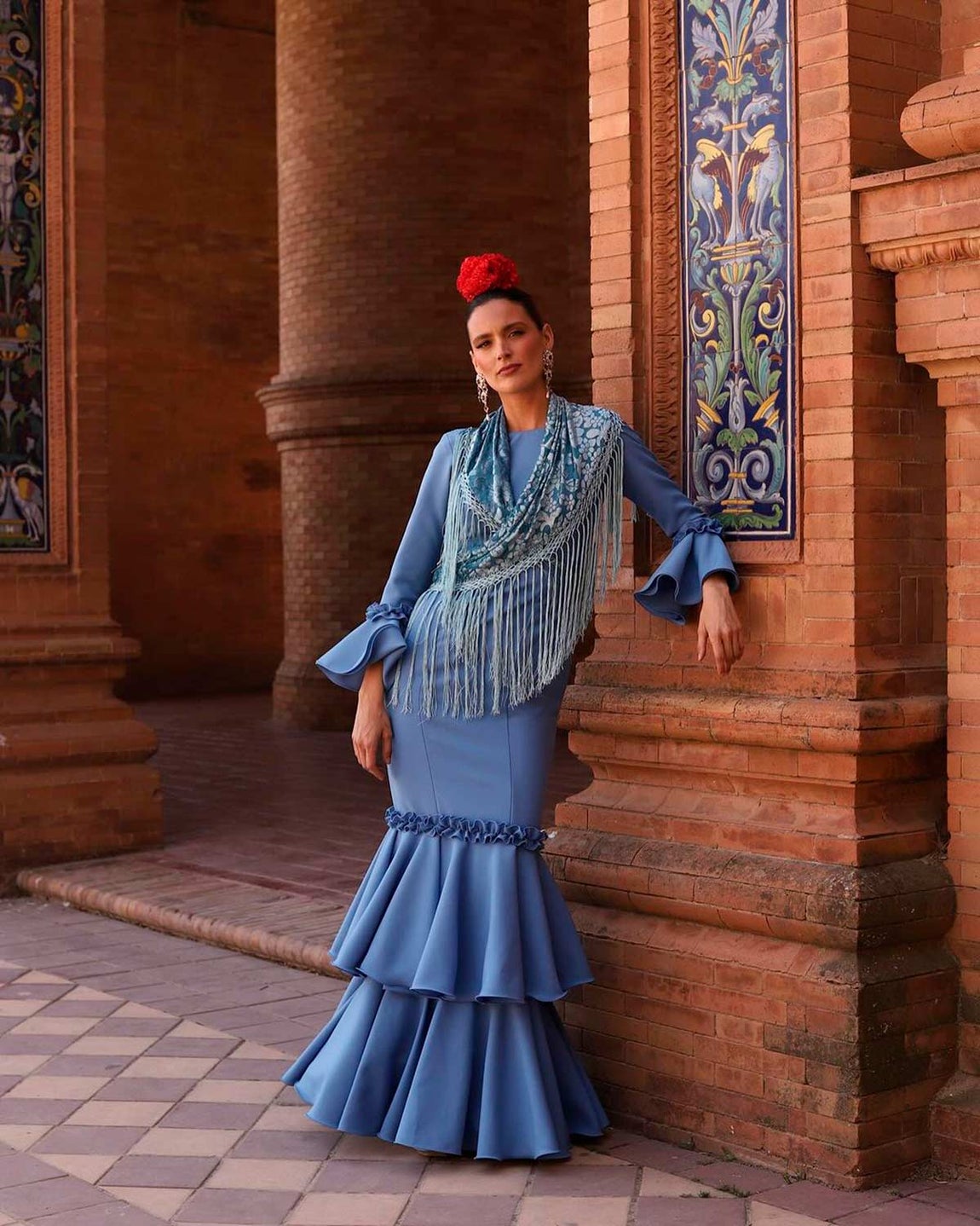 La catalana Sara Giménez se decantó por un total azul con un traje de Marcos Holland, mantón satinado del mismo color y una flor roja en el pelo. 