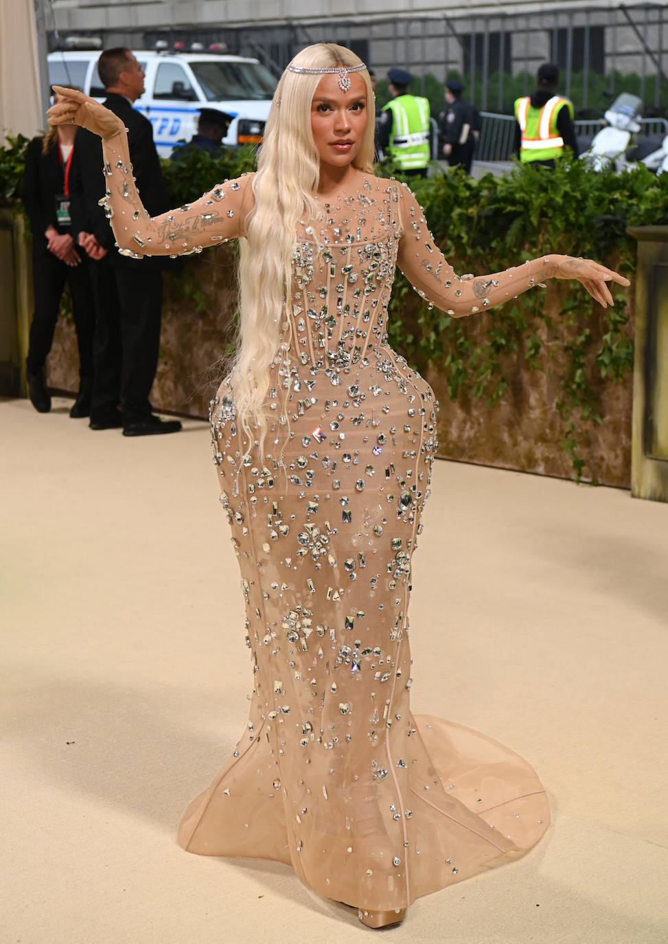 Karol G se decantó por un vestido en color nude adornado con cristales,con plataforma en las caderas. Lo combinó con su melena XXL suelta, adornada con un accesorio joya. 