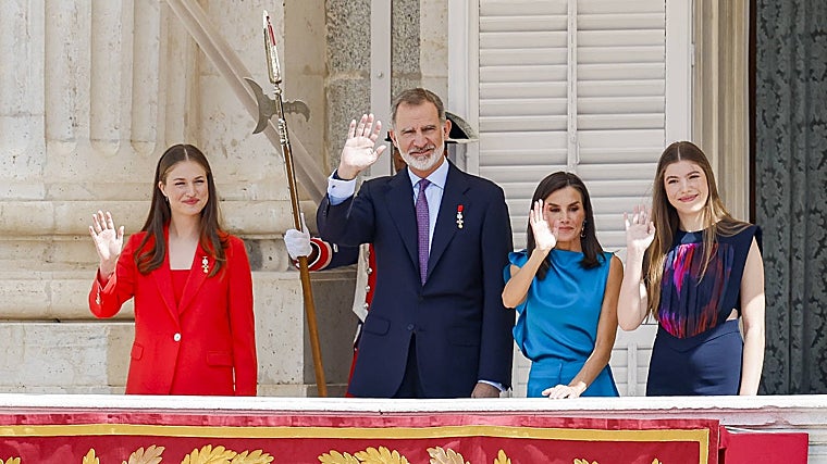 La Princesa Leonor, de rojo, el Rey Felipe VI con traje en azul marino, la Reina Letizia, con vestido azul, y la Infanta Sofía con mono azul marino en el balcón del Palacio Real.