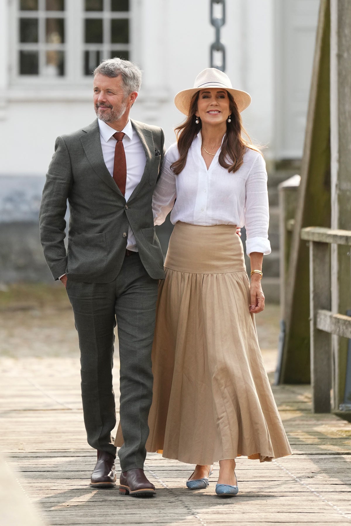 Durante su visita a Ærø el 20 de agosto, la australiana recuperó una camisa de lino de manga larga de la firma italiana Bagutta y la combinó con una falda larga de vuelo en color beige de Joseph. Remató el look con unos zapatos destalonados en azul de Jimmy Choo y su sombrero Malibú de Canopy Bay by Deborah Hutton. 