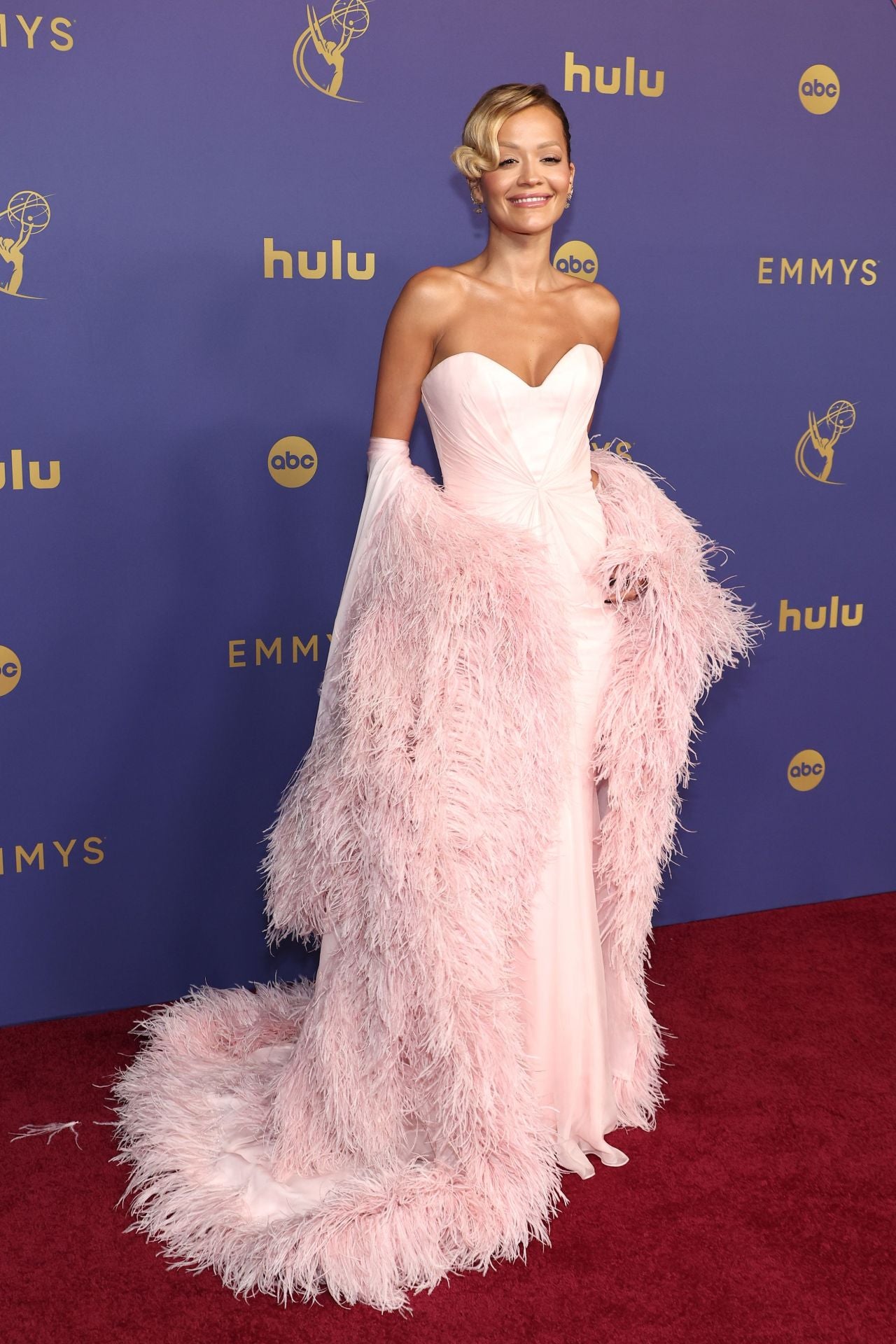 Rita Ora apareció enfundada en un diseño de un color rosa muy parecido a la tonalidad que lución Meryl Streep. La cantante combinó su  vestido palabra de honor con una llamativa capa de plumas, un diseño de Tamara Ralph.