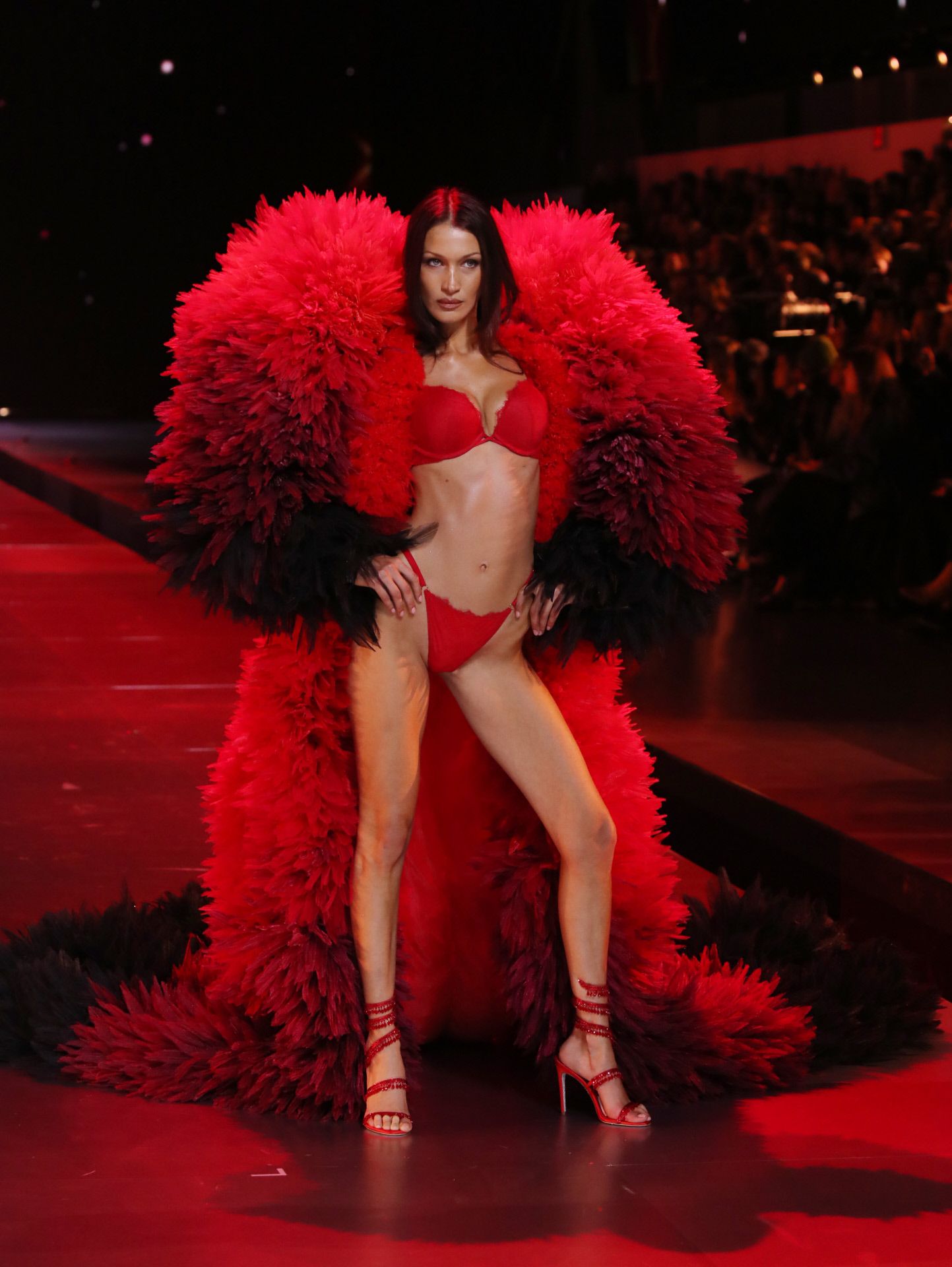 Bella Hadid desfiló con un conjunto de ropa interior en color rojo que combinó con capa XXL y sandalias de tacón. 