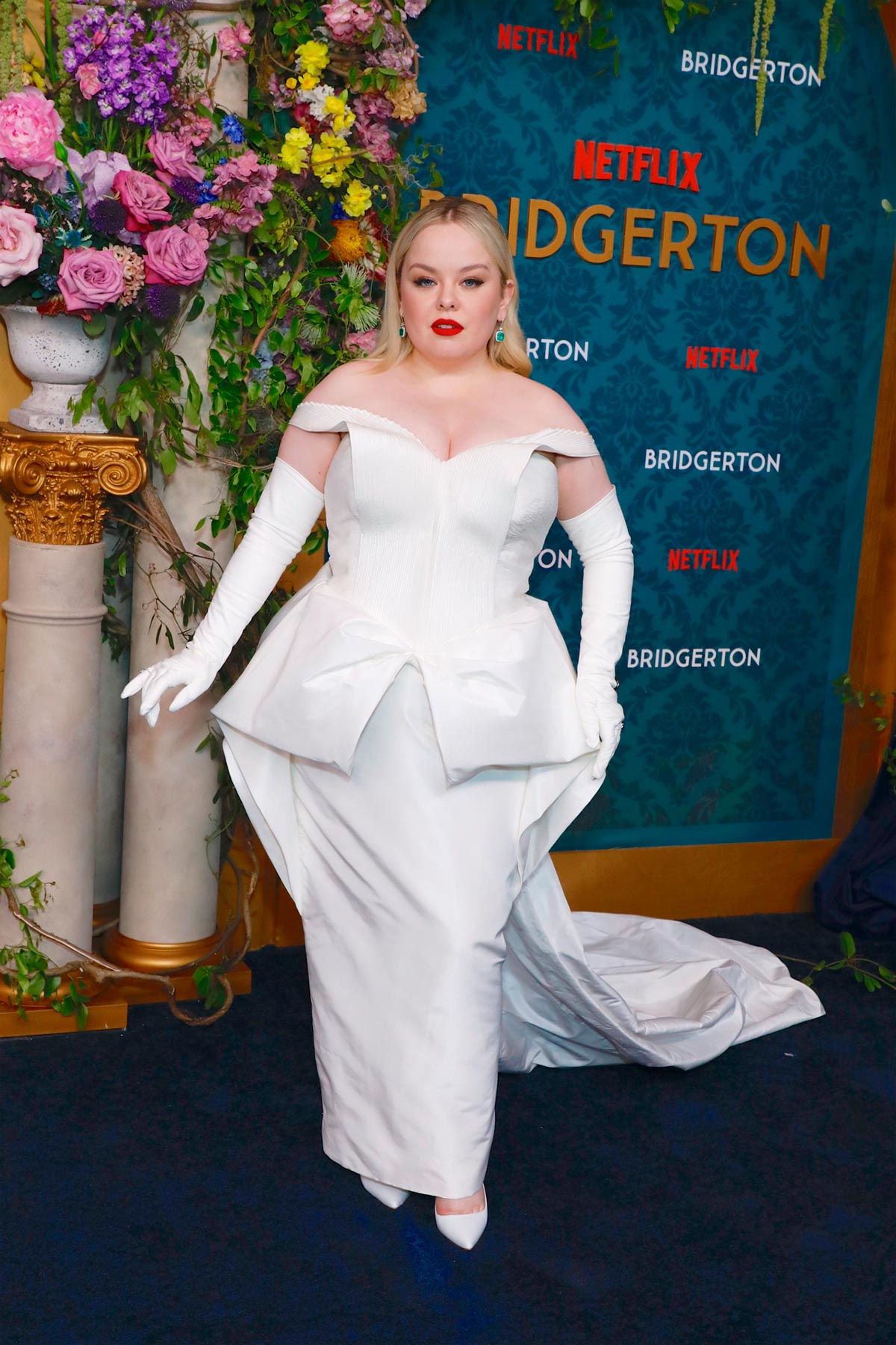 Nicola Coughlan en el estreno de la tercera temporada de 'Los Bridgerton'. La protagonista de esta entrega de la exitosa serie de Netflix hizo un guiño a su papel con este vestido de inspiración nupcial en color blanco. Un diseño de escote bardot y un peplum en la cintura con guantes largos y una gran cola. 