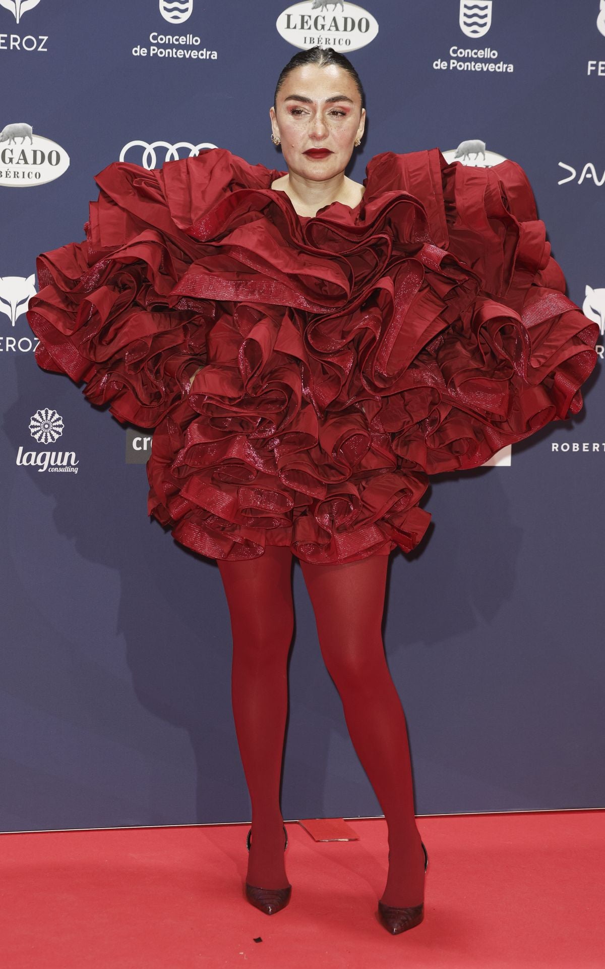 La actriz Candela Peña ha posado  en la alfombra roja de los Premios Feroz, en los que está nominada al premio como Mejor Actriz, con un Maxi vestido de volantes de tafetán granates de Redondo Brand que ha combinado con medias al tono de Calzedonia. 