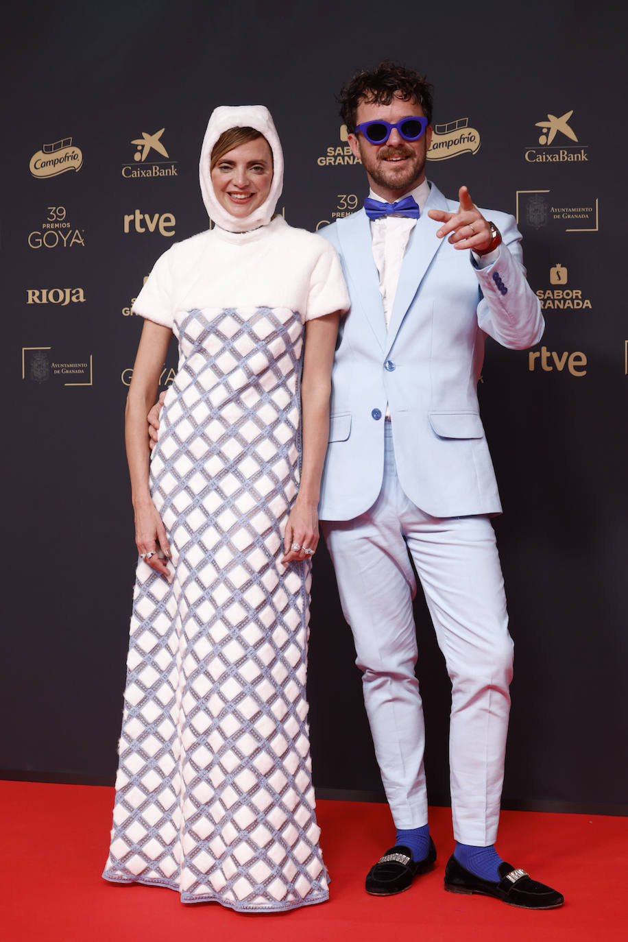 Macarena Gómez llevó un vestido blanco de Teresa Helbig, y su marido, Aldo Comas, un traje en color azul claro. La actriz lució un original tocado, debajo del cual llevó un peinado con ondas rotas elaborado por Miriam Valsera con productos de Leonor Greyl. Además, llevó joyas de la marca española Mumit. 