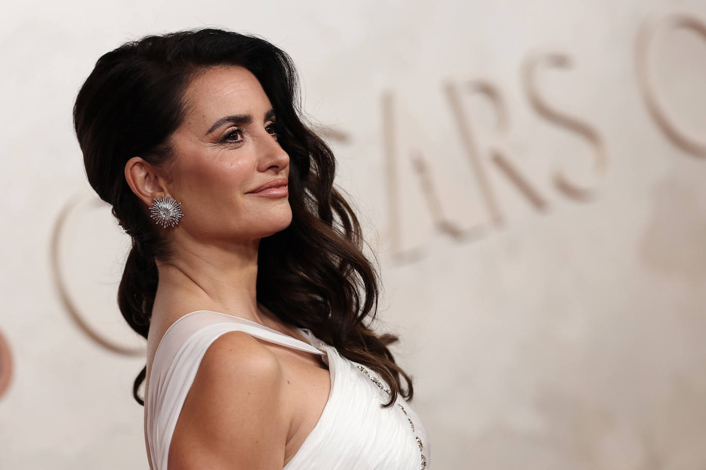 Penélope Cruz lució un semirrecogido lateral con ondas marcadas, que combinó con su habitual maquillaje: lápiz de ojos negro, pintalabios nude y colorete. 