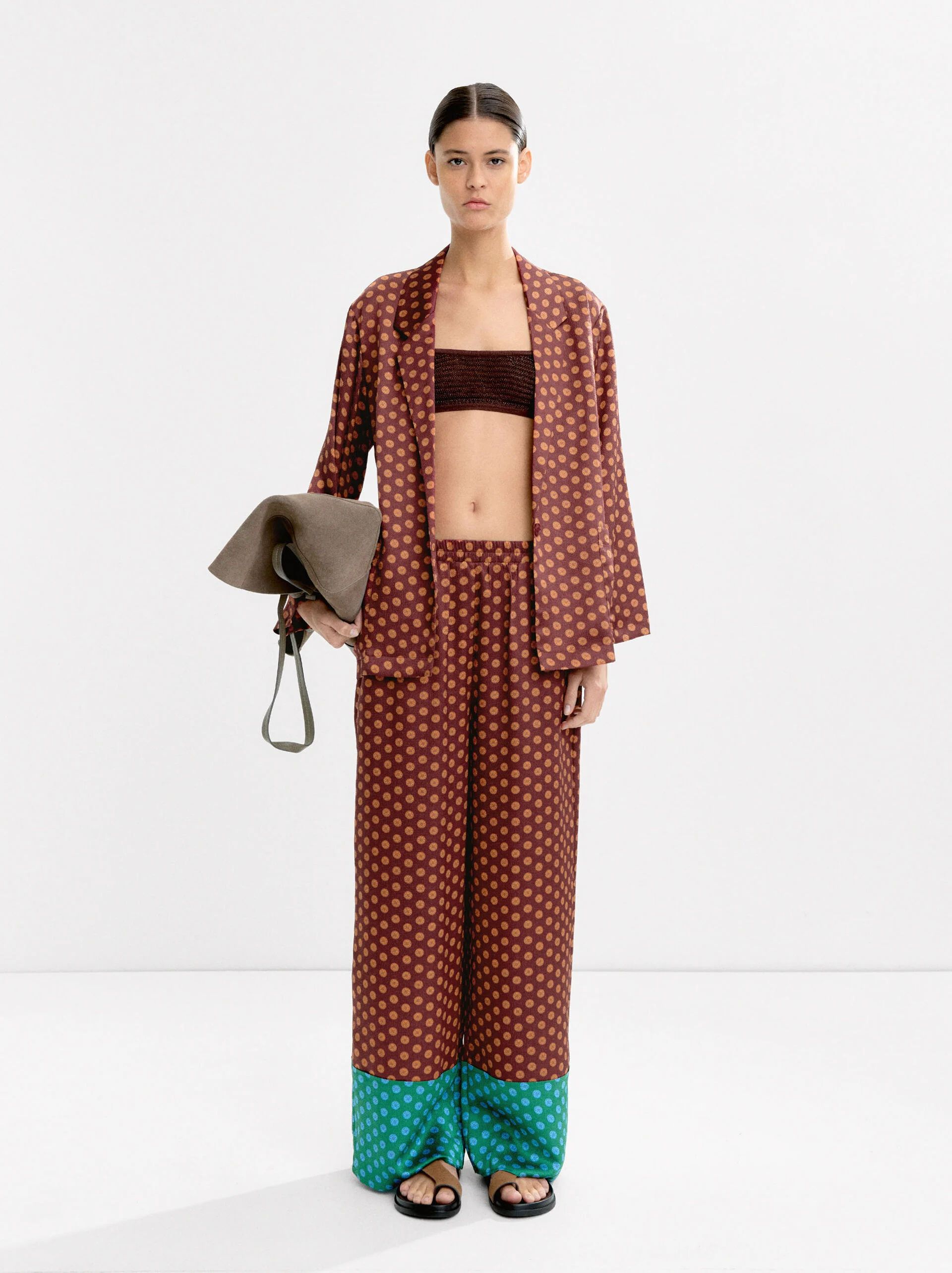 En Parfois optan por un traje de chaqueta y pantalón en tejido satinado con un llamativo estampado con fondo burdeos, pequeñas flores anaranjadas y el bajo del pantalón en turquesa a contraste. Una opción cómodo y versátil para llevar en distintos momentos del día. Precio: blazer 45,99€ y pantalón 35,99€