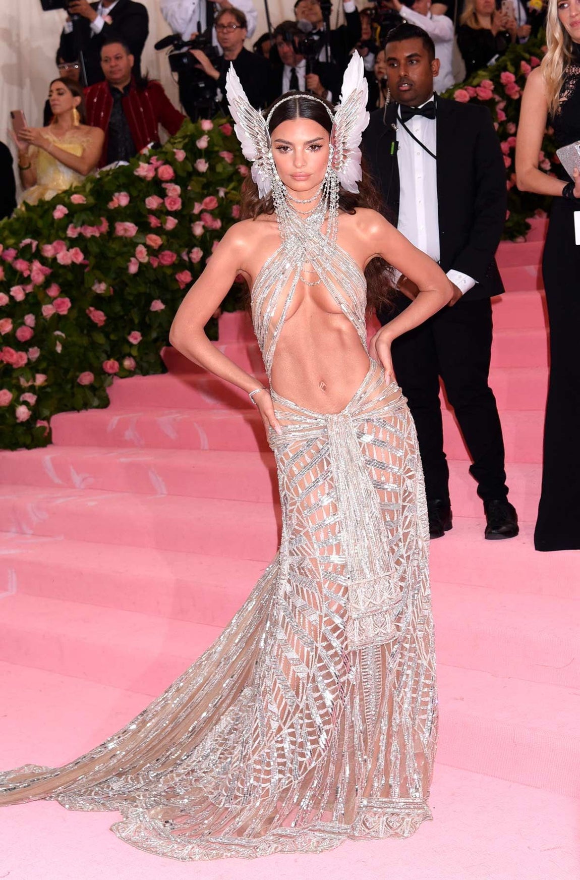En 2019, la modelo Emily Ratajkowski lució un vestido metalizado y semitransparente con el abdomen a la vista y un escote 'halter' cruzado. Firmado por Dundas, completó el conjunto con un tocado formado por unas alas de ángel de plumas a ambos lados de la cabeza.