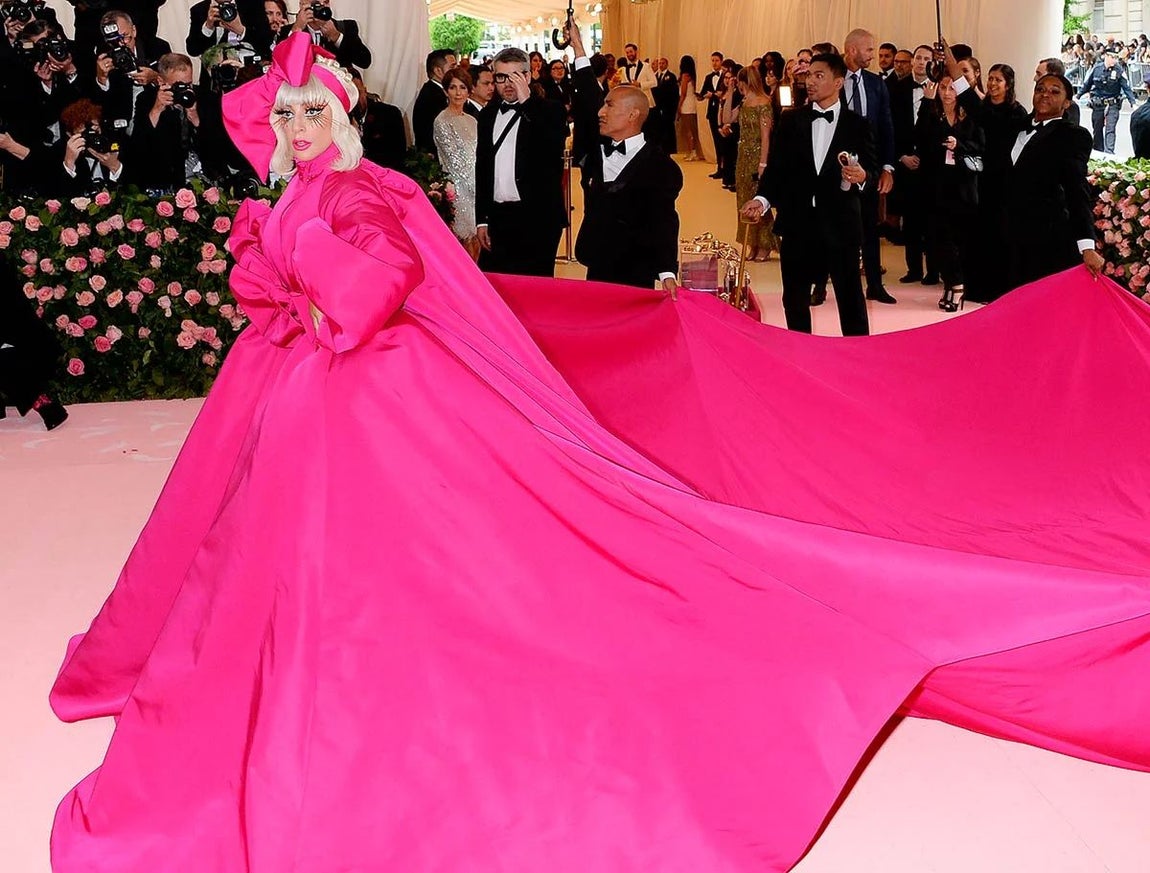 Lady Gaga eligió en 2019 un look en tono fucsia formado por abrigo-vestido con gran cola y mangas abullonadas del diseñador Brandon Maxwell. Lo combinó con maquillaje con maxi pestañas.