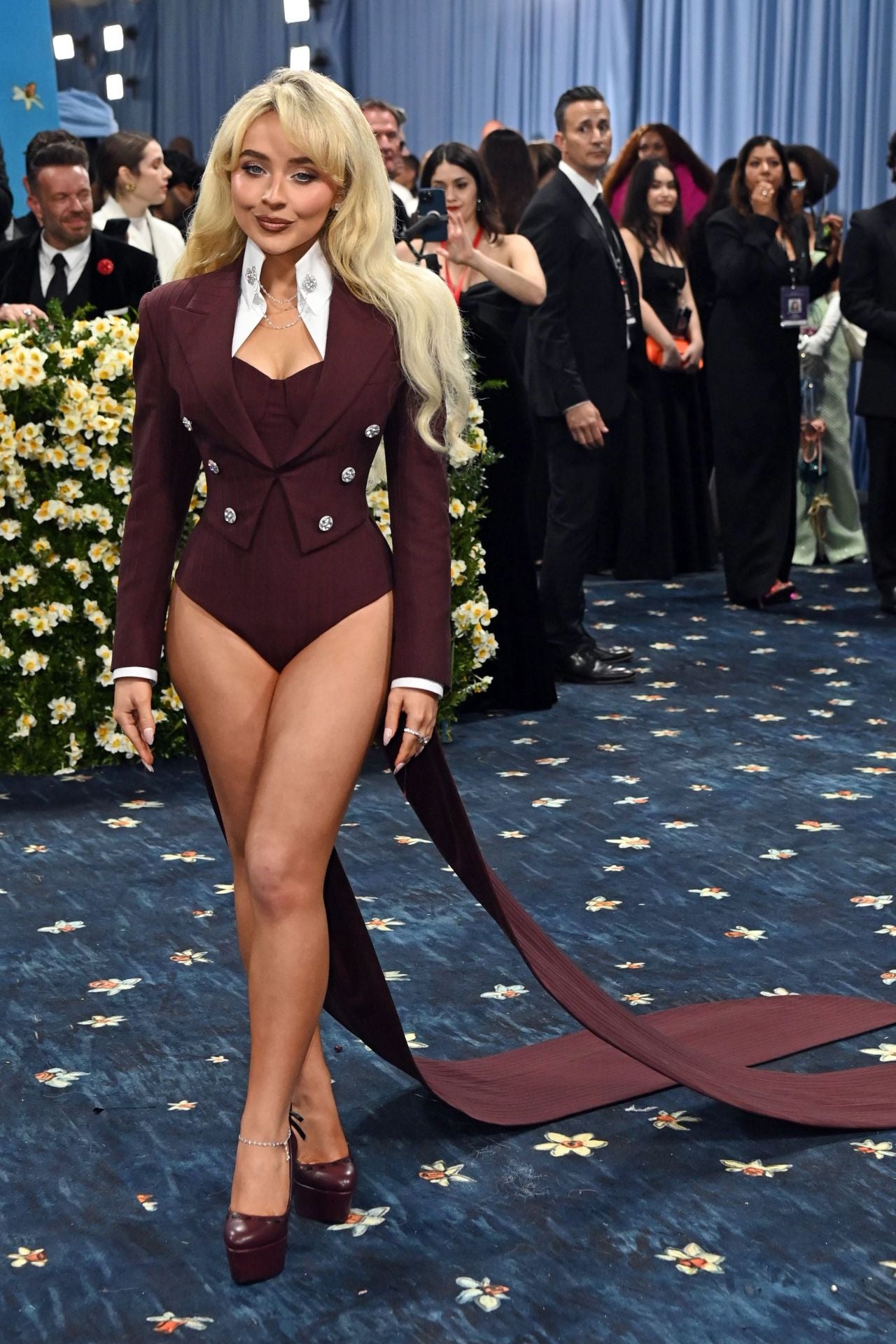 Sabrina Carpenter con un llamativo traje con body y cola en color burdeos de Louis Vuitton