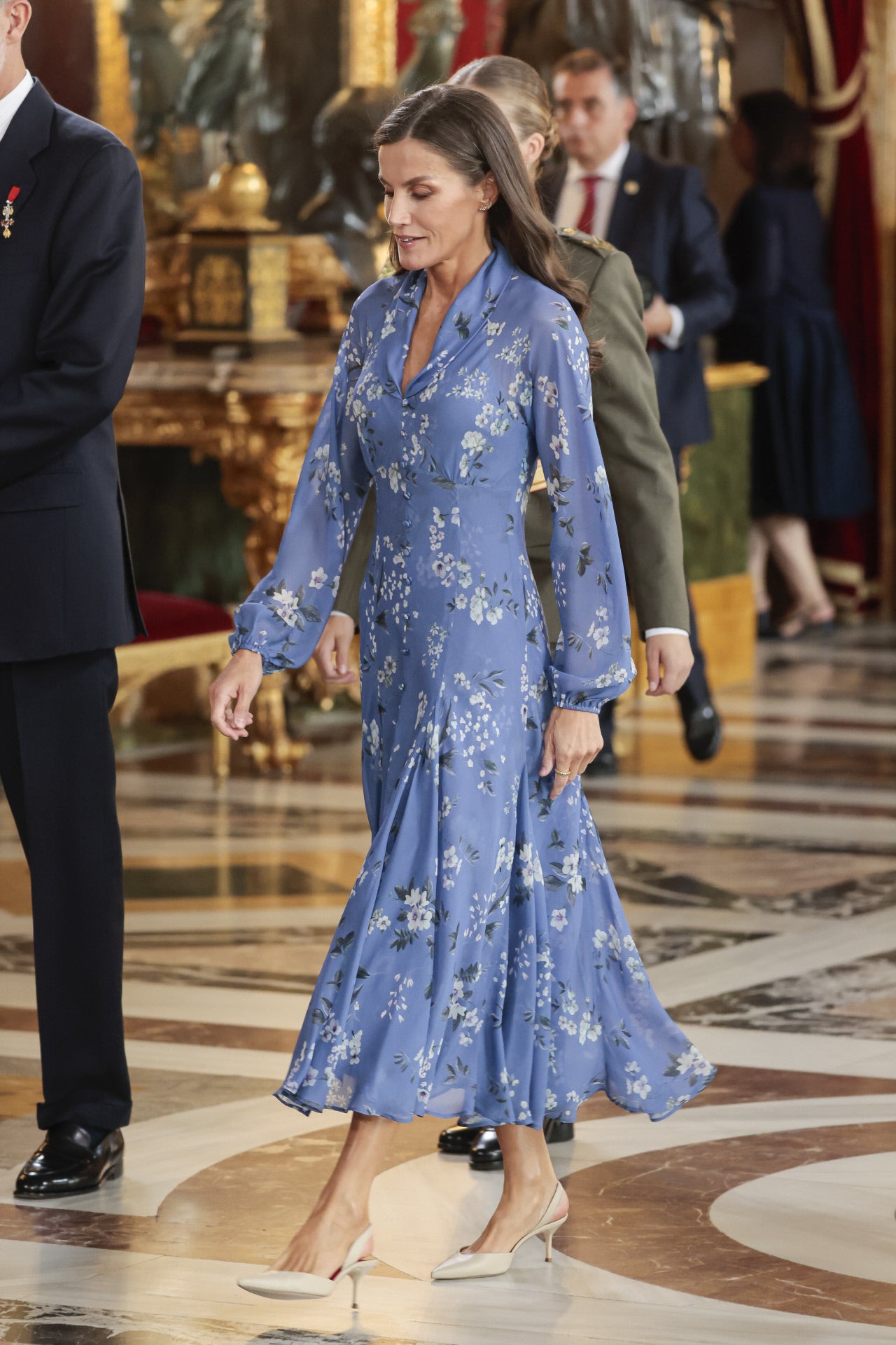 En 2023, la Reina Letizia lució un precioso vestido azul con estampado floral de la firma española Juan Vidal. Acompañado de unos salones blancos, el vestido de falda de gran vuelo y mangas largas fue un gran acierto de su Majestad para la ocasión. 