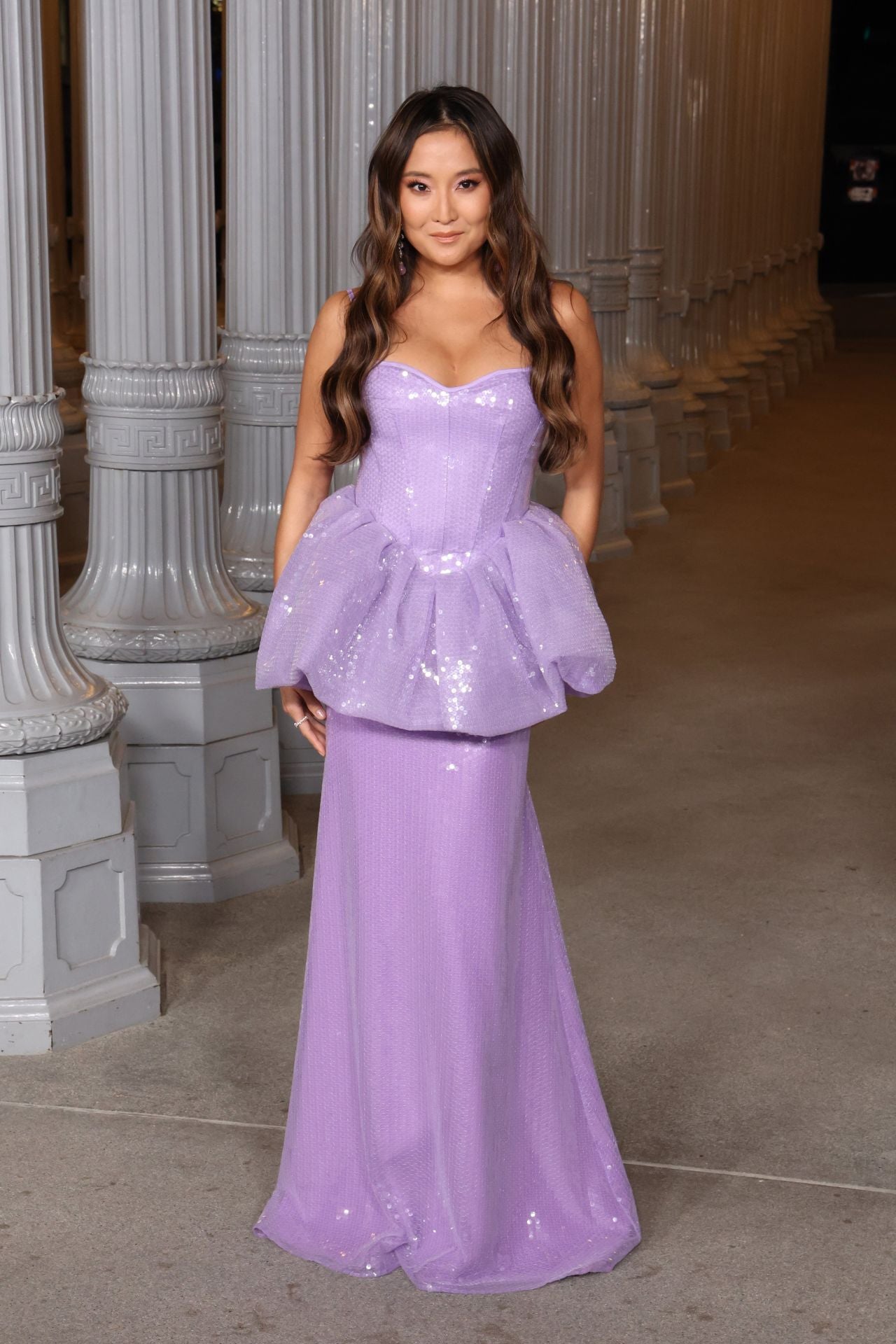 Ashley Park con vestido de lentejuelas en color malva con escote palabra de onor y peplum