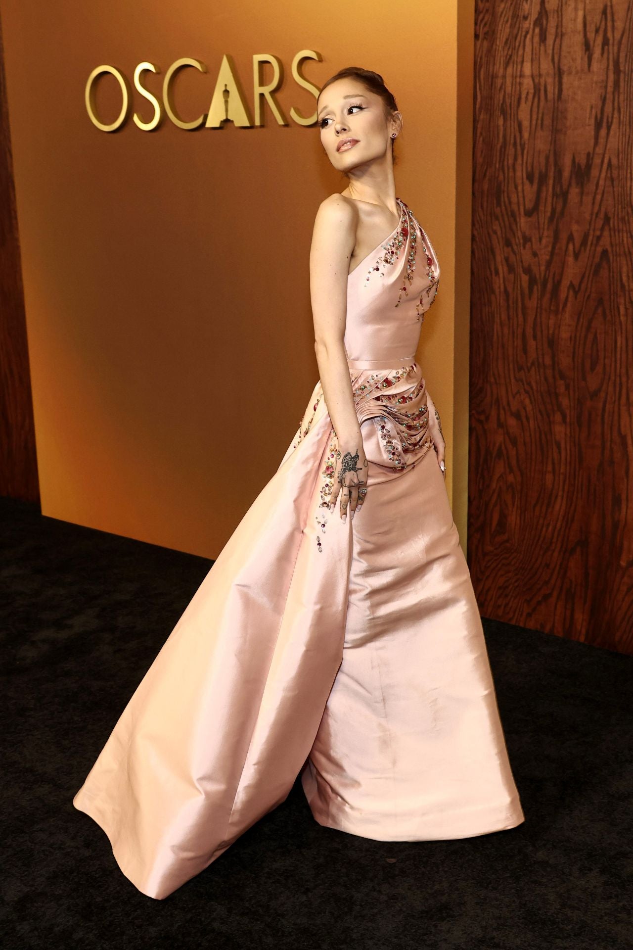 Ariana Grande se decantó por un vestido de archivo de la colección Otoño/Invierno 2007 de Dior. Se trata de un diseño realizado en tejido satinado con detalles bordados, escote asimétrico y drapeados a la cadera. 