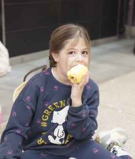 Imagen secundaria 2 - Los menores han estado también jugando durante la jornada (arriba); Lourdes Montes y Juan Llorca, padrinos del evento (izquierda); los alumnos del colegio han estado también comiendo manzanas durante el evento.