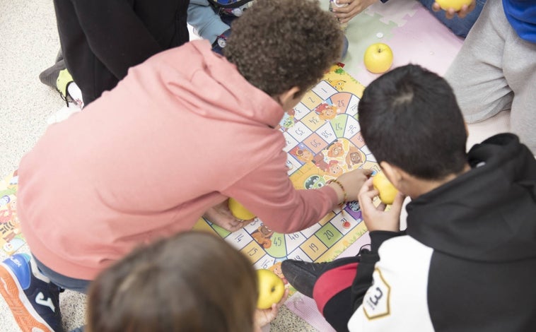 Imagen principal - Los menores han estado también jugando durante la jornada (arriba); Lourdes Montes y Juan Llorca, padrinos del evento (izquierda); los alumnos del colegio han estado también comiendo manzanas durante el evento.