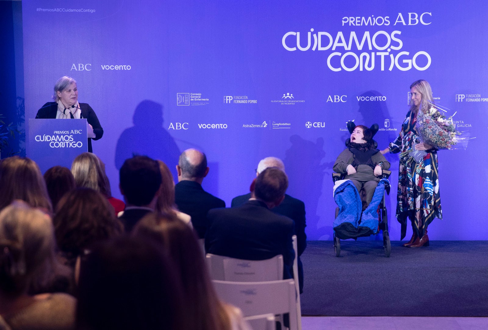 Eva Gómez , madre de Elsa, fue reconocida con el premio Cuidador del Año. Hizo entrega del galardón Carina Escobar, presidenta de la Plataforma de Organización de Pacientes. En la imagen, Carina aparece junto a Elsa mientras su madre agradece el galardón