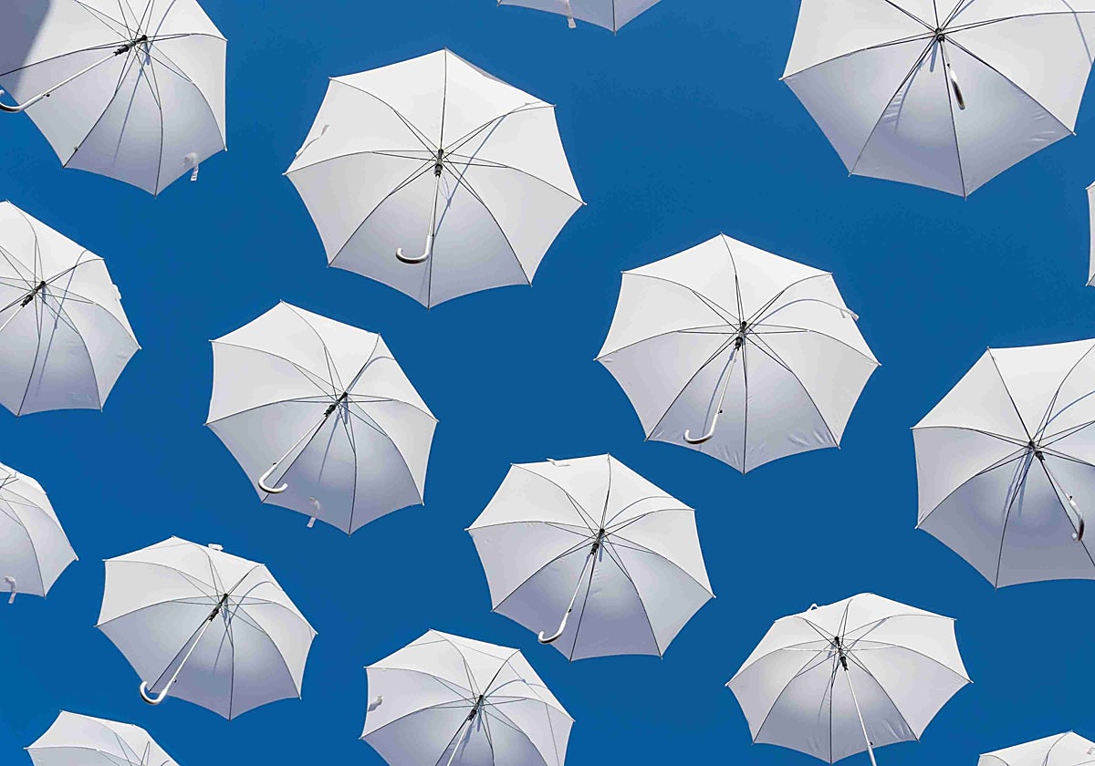 Ilustración de paraguas plegables abiertos en un cielo azul
