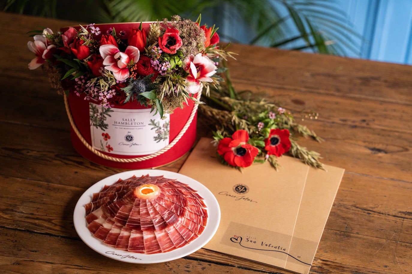Cinco Jotas y Sally Hambleton se unen este año para crear un regalo especial, una edición limitada de un pack conformado por una ración -cortada y emplatada a mano- del exquisito jamón de bellota 100 % ibérico acompañado por un ramo de flores frescas de la florista más deseada de Madrid. Hay distintos formatos, que van desde los 95 a los 185 euros si se incluye la sombrerera artesanal, en www.sallyhambleton.com