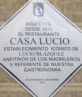 Imagen secundaria 2 - Sobre estas líneas, Lucio Blázquez junto al alcalde de Madrid, José Luis Martínez-Almeida, su hija María Blázquez, y la vicealcaldesa Begoña Villacís, en Casa Lucio. Abajo, los cocineros Paco Roncero (izq.), Pepa Muñoz, Alberto Chicote, Sacha Hormaechea y Mario Sandoval durante el homenaje. A la derecha, la placa que luce desde este martes 7 de febrero en la fachada del restaurante.