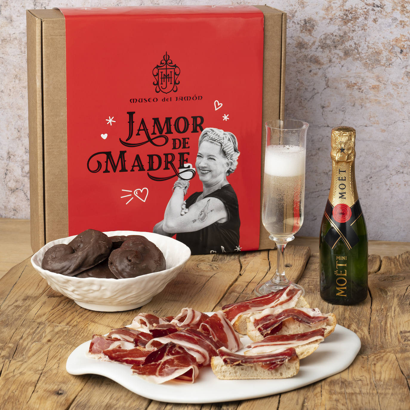 Bajo el nombre de 'Jamor de madre', el Museo del Jamón lanza un pack especial de edición limitada para disfrutar en este día tan señalado. La caja contiene un sobre de jamón ibérico de bellota 50%, acompañado de un champán francés y unas  palmeritas de chocolate, horneadas en su obrador propio que el grupo madrileño posee en Avenida de Córdoba, donde hacen cada día el pan. Está disponible por 55 euros tan solo en tienda.