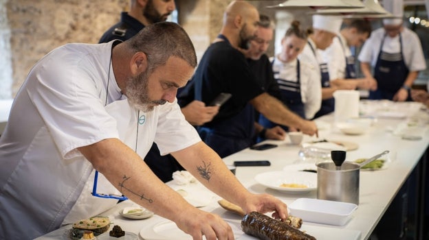 El chef de Aponiente con su 'porchetta marina'. Detrás, Albert Adriá hablando con el equipo