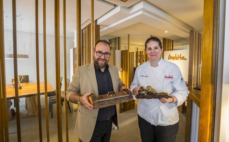 Imagen principal - Sobre estas líneas (arriba), Elena Lucas y Diego Muñoz, chef y jefe de sala respectivamente de La Lobita (Navaleno, Soria), una estrella Michelin. Abajo, vistas desde la sala de La Lobita a los pinares de Urbión. a la derecha, uno de los platos de su menú actual: patitas de codorniz en salsa Périgourdine, royale de su propias pechugas asadas y trufa negra