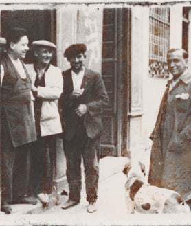 Imagen secundaria 2 - Sobre estas líneas, arriba, foto antiguia de la fachada del restaurante Casa Duque de Segovia, donde se podía leer 'Antigua Casa El Chato', apodo de Dionisio Duque, primera generación de la familia y fundador de Casa Duque. Abajo, a la izquierda, uno de los salones del restaurante en 1928. A la derecha, Julián Duque, segunda generación de la saga familiar en la puerta de la calle Cervantes 12 de Segovia en la que siempre ha estado ubicado este negocio.