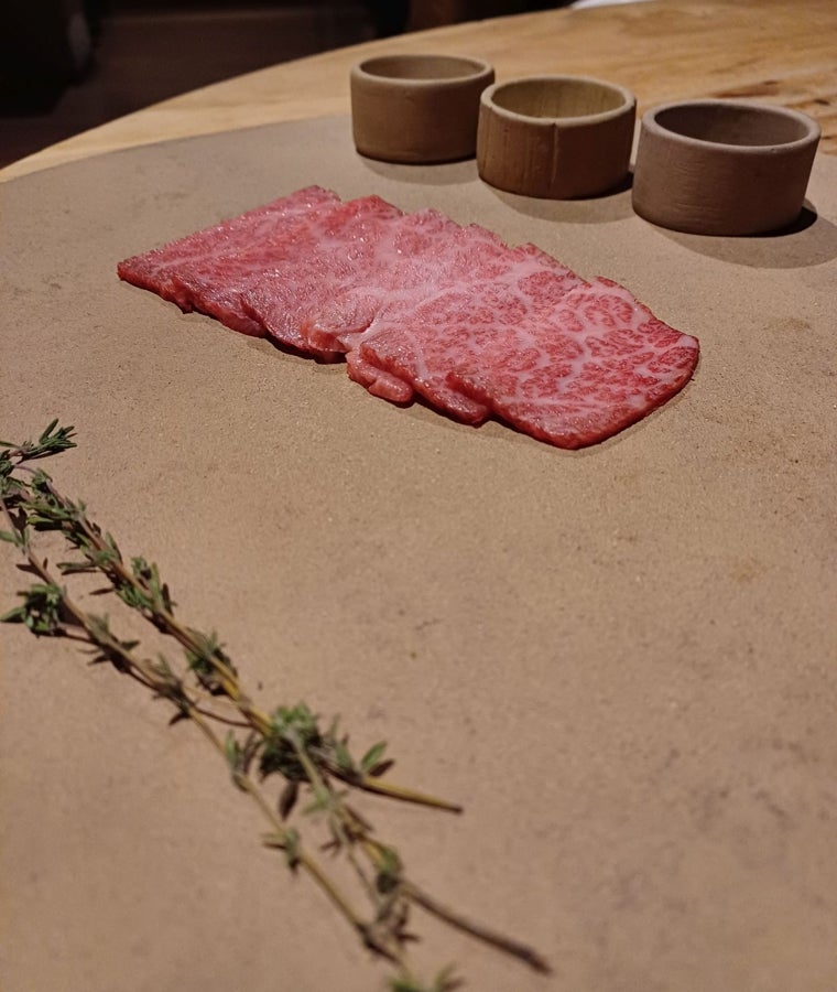 Cortes de wagyu matsusaka listos para tocar en la parrilla y aromatizar, si se desea, con unas ramas de tomillo echándolas al carbón antes