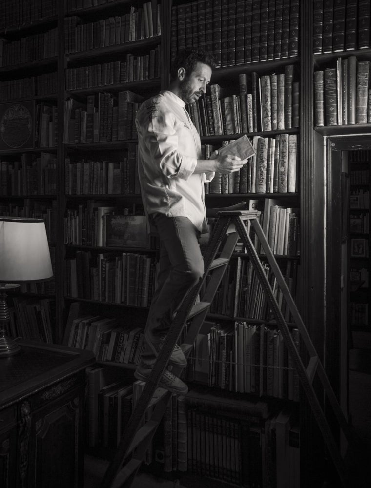 Iván Cerdeño subido a la escalera de la biblioteca del Cigarral de Menores mientras busca un ejemplar de uno de los recetarios antiguos con los que trabaja en su restaurante. Este espacio fue habitado por Gregorio Marañón durante décadas